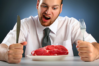 Un homme avec des couverts en face d'un steak.