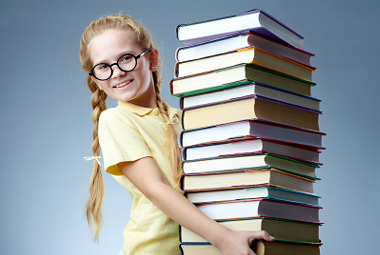 Une fille souriante avec une pile de livres.