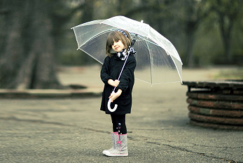 Une petite fille debout avec un parapluie dans le parc, en attendant la pluie.