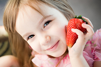 Fille avec une fraise géante.
