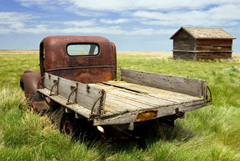 Une vieille camionnette rouillée dans un champ vert.