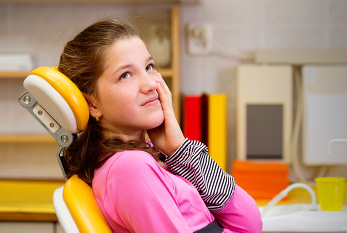 Une jeune fille avec les maux de dents chez le dentiste.