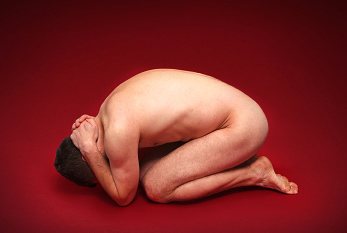 Humilié homme recroquevillée sur le sol, comme un symbole de victimes de la torture.