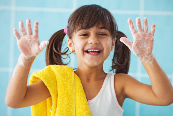 Une jeune fille en riant avec du savon sur vos mains.