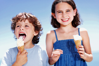 Un garçon et sa sœur en appréciant leur crème de glacée à l'extérieur.