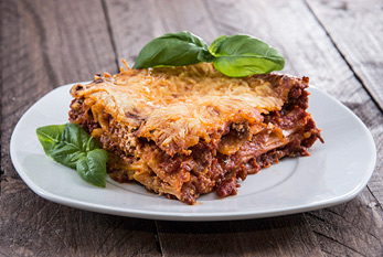 Lasagne maison frais sur une assiette décorée avec du basilic.