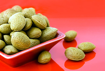 Quelques amandes dans une soucoupe rouge.