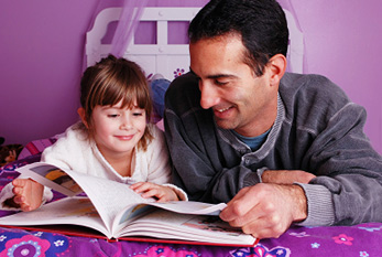Une petite fille lisant un conte de fées avec son père.