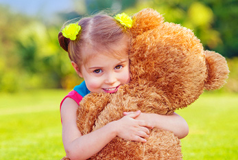 Jeune fille câlins avec un ours en peluche à l'extérieur pendant un pique-nique.